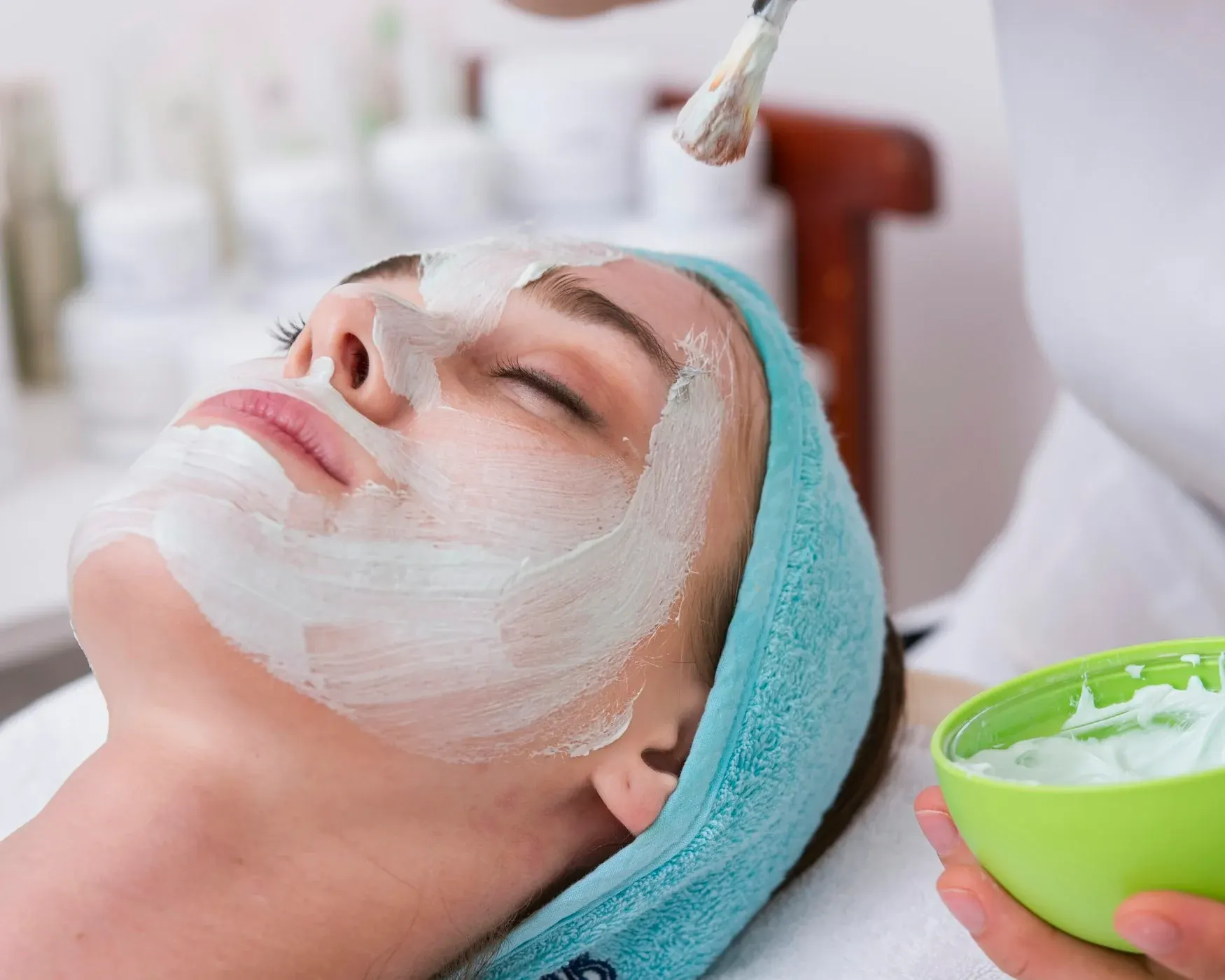 Un’estetista applica una maschera viso con il pennello a una cliente